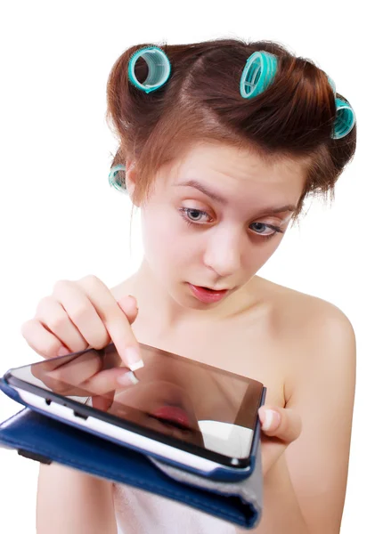 Surprised young woman in a bath towel and hair curlers with tablet computer in her hands. Close-up. — Stock Photo, Image