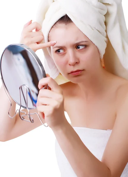 Junges Mädchen mit Handtuch auf dem Kopf, sieht sein Gesicht im Spiegel. Stockbild