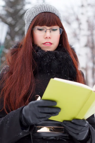 Girl with a book in a snowy park — Fotografia de Stock