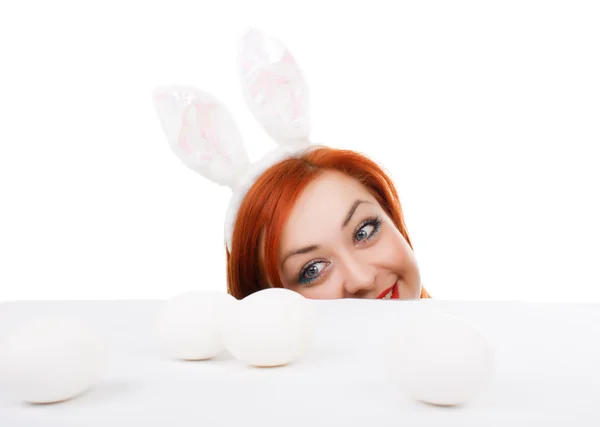 Conejito de Pascua hembra mirando por encima de la mesa para huevos de Pascua — Foto de Stock