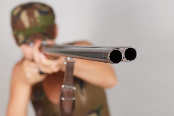 Una cazadora con un arma apunta. Fondo gris — Foto de Stock