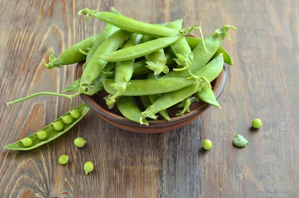 Guisantes verdes en un tazón sobre un fondo de madera —  Fotos de Stock