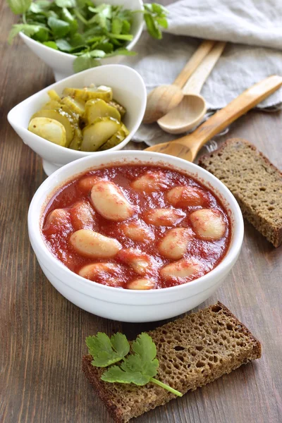 White beans in tomato sauce served with pickled cucumbers — Stock Photo, Image
