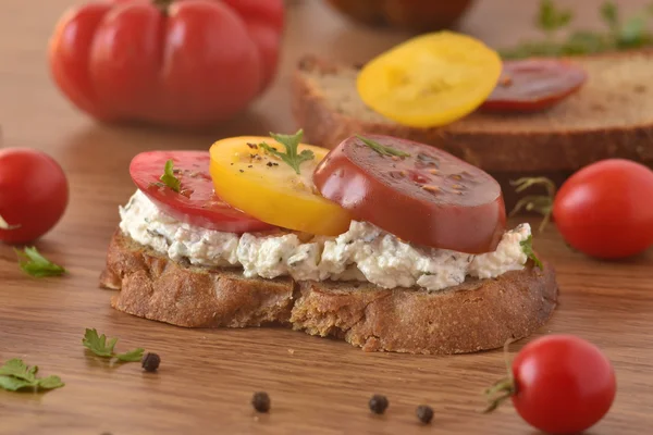 Sandwich of rye bread with cream cheese, tomatoes and herbs — Stock Photo, Image