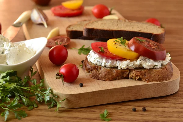 Panino di pane di segale con crema di formaggio, pomodori ed erbe aromatiche — Foto Stock