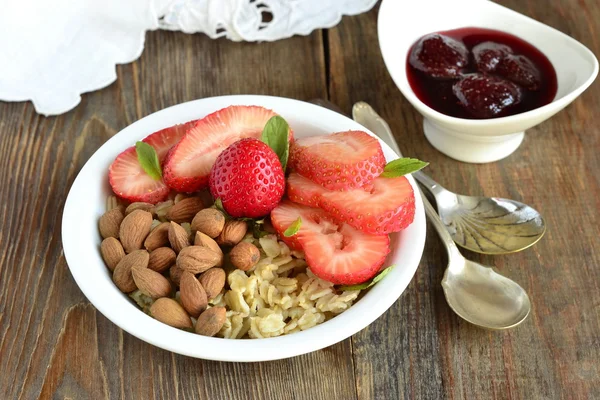 Oatmeal porridge, fresh strawberries, almonds and jam — Stock Photo, Image