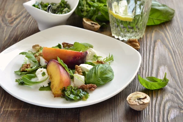 Салат с персиками, ругулой, сливочным сыром, песто и грецкими орехами — стоковое фото
