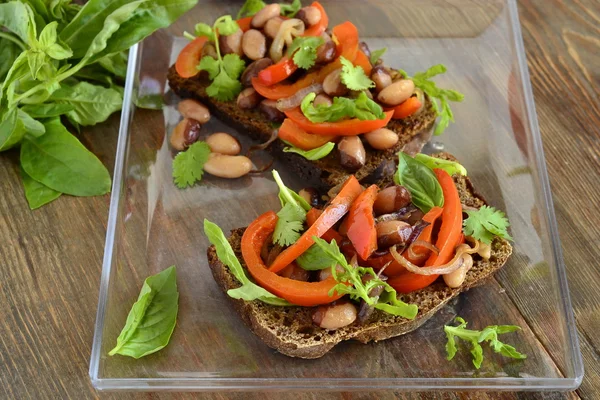 Rye bruschetta with beans, sweet peppers, arugula and red onion — Stock Photo, Image
