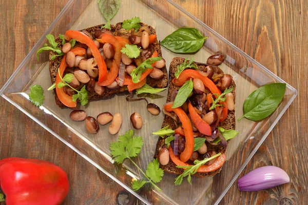 Rye bruschetta with beans, sweet peppers, arugula and red onion — Stock Photo, Image