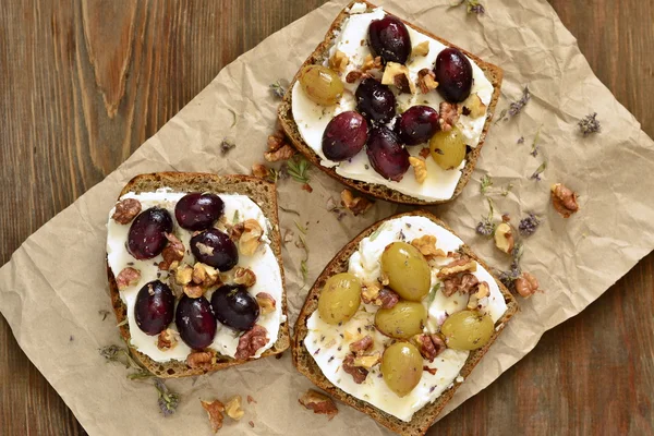 Crostini com uvas torradas, queijo de cabra, nozes e mel — Fotografia de Stock