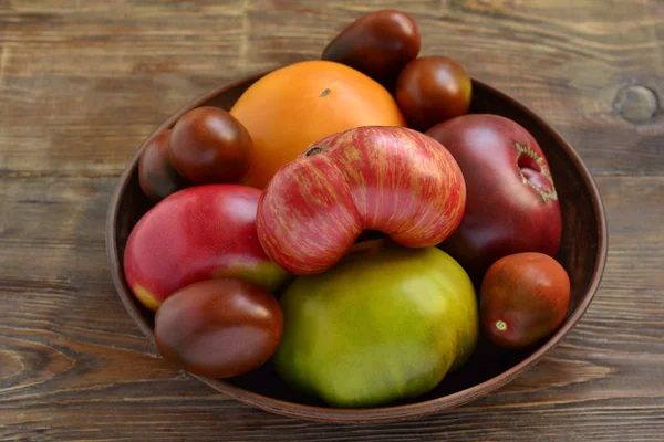 Различные помидоры на деревянном фоне — стоковое фото