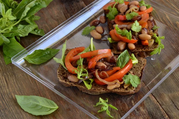 Bruschetta de centeio com feijão, pimentão doce, rúcula e cebola vermelha — Fotografia de Stock