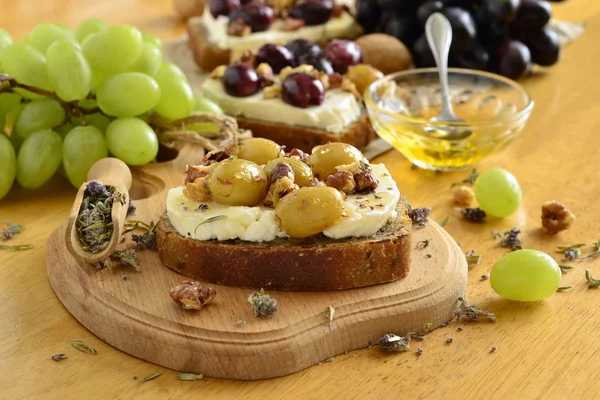 Crostini com uvas torradas, queijo de cabra, nozes e mel — Fotografia de Stock