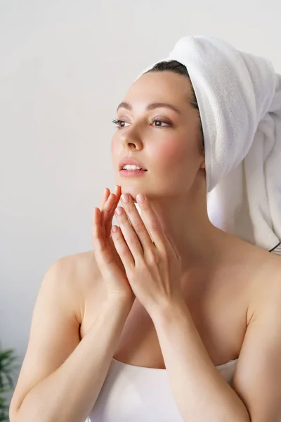 Jonge mooie vrouw met een perfecte huid, die haar gezicht aanraakt. Cosmetologie, schoonheid en spa concept. — Stockfoto