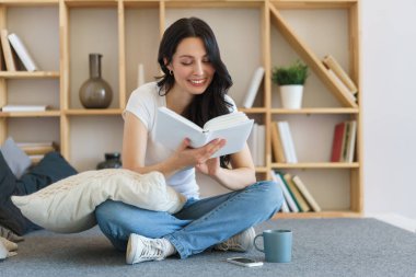 Hafta sonları evde oturup kitap okuyan hoş bir genç kadın..