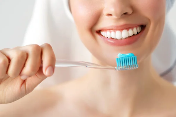 Glimlachende vrouw die haar tanden schoonmaakt met een tandenborstel in een tandhygiëne concept. geïsoleerd op wit — Stockfoto