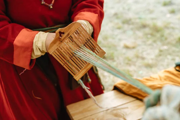 Weaving craft. Woman in traditional dress works with hands