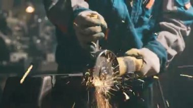 Özel kıyafet ve gözlüklü bir çilingir üretim işinde çalışıyor. Açı öğütücüyle metal işleme. Metal işçiliğinde kıvılcımlar