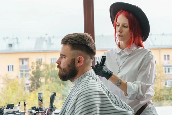 Coiffeur professionnel utilise une tondeuse à cheveux pour la barbe frangeante pour un bel homme dans le salon de coiffure — Photo