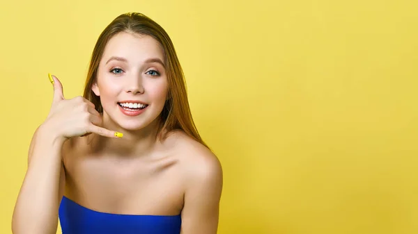 Una joven sonriente haciendo un gesto para representar una conversación telefónica. Concepto de servicio de consulta telefónica. Centro fresco cartel de promoción —  Fotos de Stock