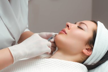 Bir kozmetoloji salonunda dudak büyütme ve düzeltme prosedürü. Uzman hasta dudaklarından iğne yapıyor..