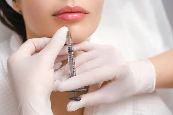 Lippenvergrößerung und Korrektur in einem Kosmetiksalon. Der Spezialist spritzt dem Patienten eine Spritze in die Lippen. — Stockfoto