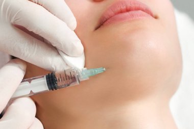 Doktor kozmetik uzmanı, güzellik salonundaki genç ve güzel bir kadının cildindeki kırışıklıkları sıkılaştırmak ve düzleştirmek için canlandırıcı yüz enjeksiyonu prosedürünü uyguluyor. Kozmetoloji, cilt bakımı