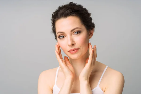 Jonge mooie vrouw met een perfecte huid, die haar gezicht aanraakt. Cosmetologie, schoonheid en spa concept. — Stockfoto