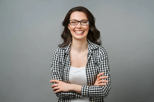 Retrato de negocios de una joven. Una morena sonriente con gafas mira a la cámara, sus brazos cruzados sobre su pecho. — Foto de Stock
