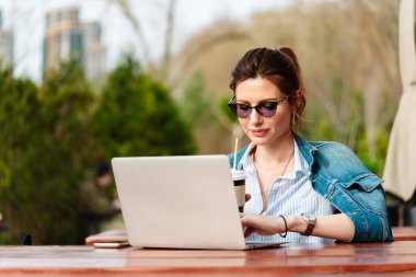 Young woman working at a laptop in a cafe on an outdoor veranda