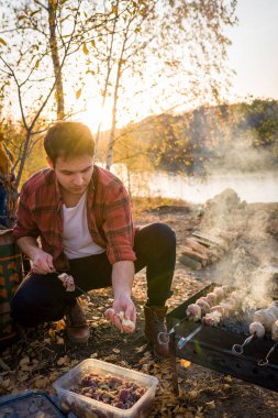 Çift doğada dinleniyor. Doğada barbekü hazırlayan adam