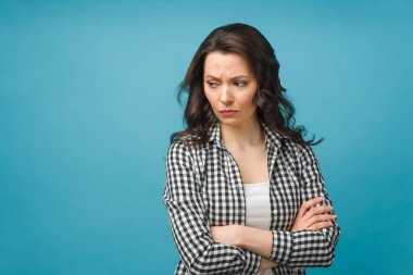 Portrait of an angry young woman standing over isolated blue background.