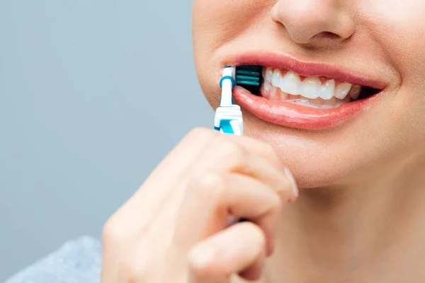 Kvinna med friska vita tänder håller en tandborste och ler. Begreppet munhygien — Stockfoto