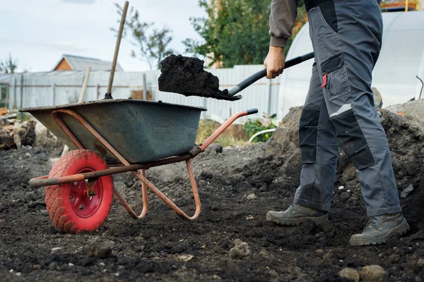 Работа с садовыми инструментами, лопатой и тачкой на месте загородного дома. подготовка к строительным работам. — стоковое фото