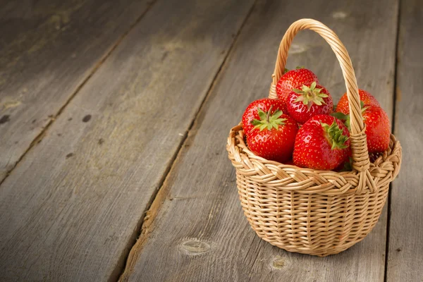 Strawberries in basket on a wooden table Royalty Free Stock Photos