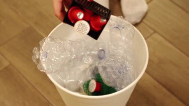 İnsan ortaya çıkar ve plastik atıkları özel bir çöp kutusuna atar.
