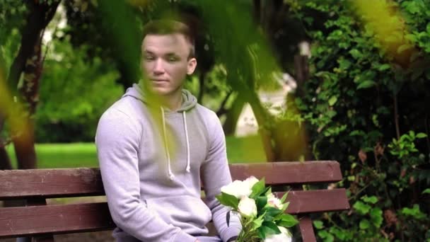 Homme émotionnel avec des fleurs blanches est assis en attente de la date — Video