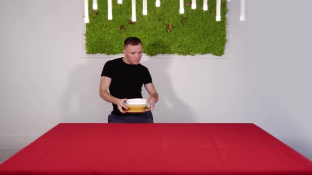 Радостный мужчина в черной футболке приближается к красному столу — стоковое видео