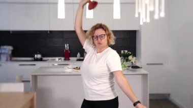 Aktif sarışın dans eder ve elinde kırmızı lavabo pompasıyla şarkı söyler.