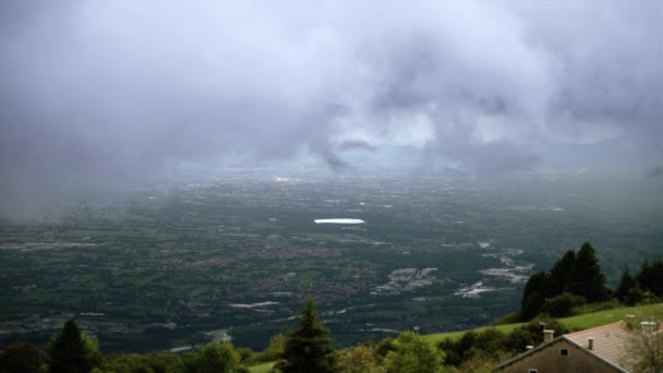 Schwere Wolken schweben über grünem Hügel mit Hütte in Talnähe — Stockvideo