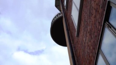 Geniş yuvarlak balkon kapaklı kırmızı tuğlalardan yapılmış bina.