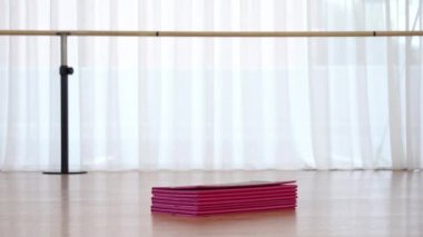 Çoraplı kadın, spor salonunda katlanmış pembe paspaslar ve desteler getiriyor.