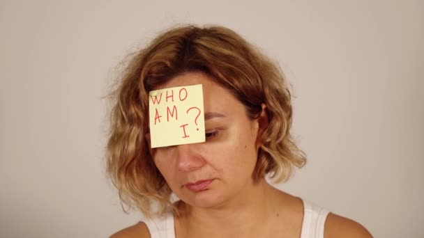 Молодая блондинка исполняет депрессивные эмоции с бумажной наклейкой — стоковое видео