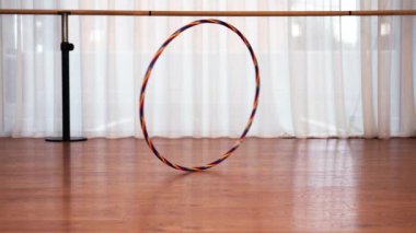 Büyük renkli hula hoop dönüşleri kahverengi zemine düşer.