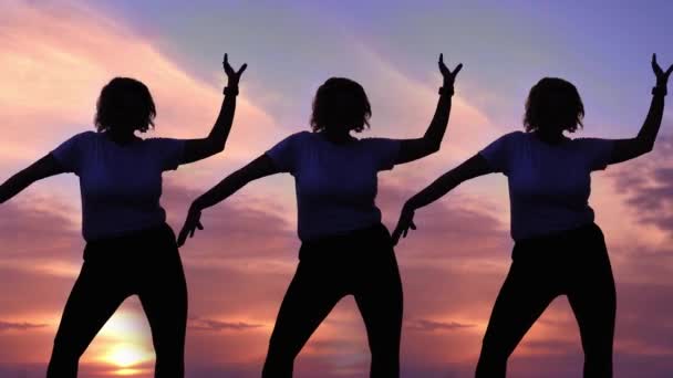 Baculatá žena silueta tance třesoucí se ruce proti západu slunce — Stock video