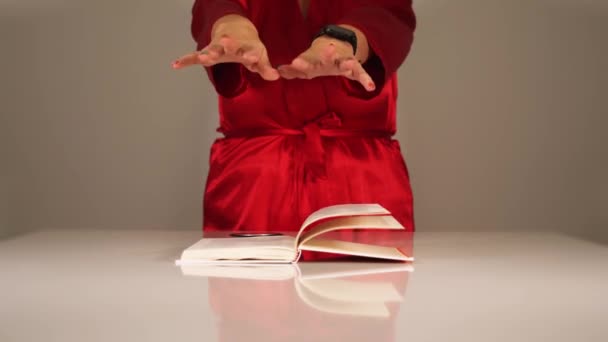 Дама в червоному халаті тримає руки над поверненням на вітрові сторінки — стокове відео