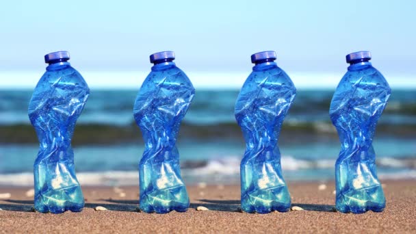 Reihe zerknüllter blauer Plastikflaschen stehen auf Sand am Strand — Stockvideo