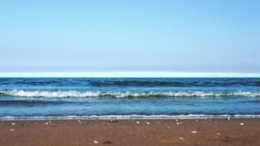 Endless sea waves roll with white foam on sand in summer
