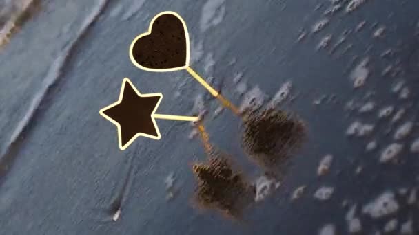 Foamy waves roll to blank star and heart nameplates in sand — Stok video