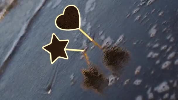 Foamy waves roll to blank star and heart nameplates in sand — Video Stock